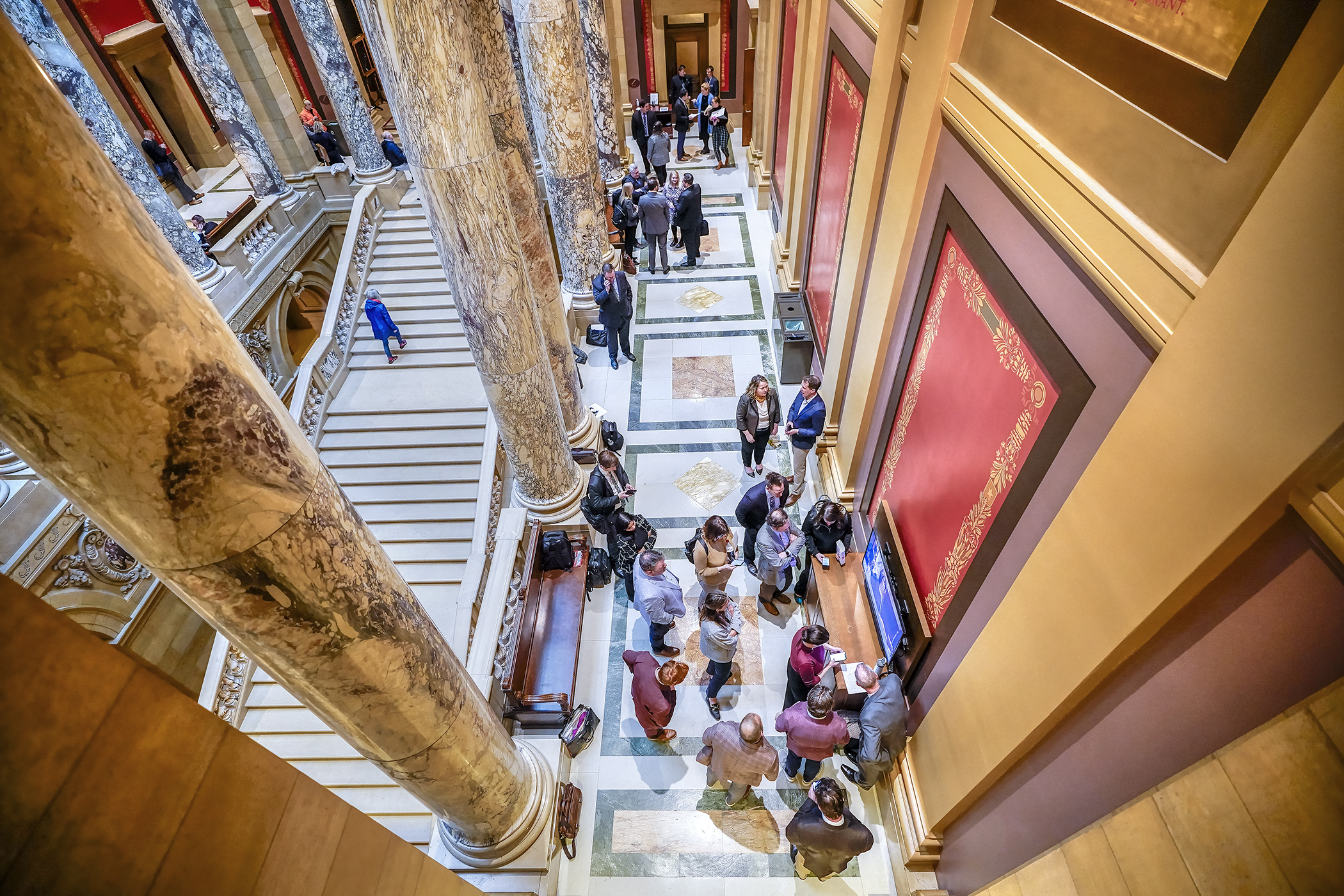 Interested parties watch Monday’s legislative activity on one of the monitors in a State Capitol hallway. The corridors will see a flurry of activity in the last weeks of a session that must end by May 20. (Photo by Andrew VonBank)